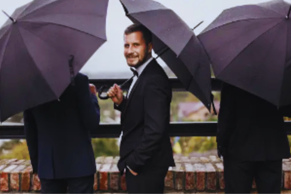 novio e invitados a la boda bajo la lluvia